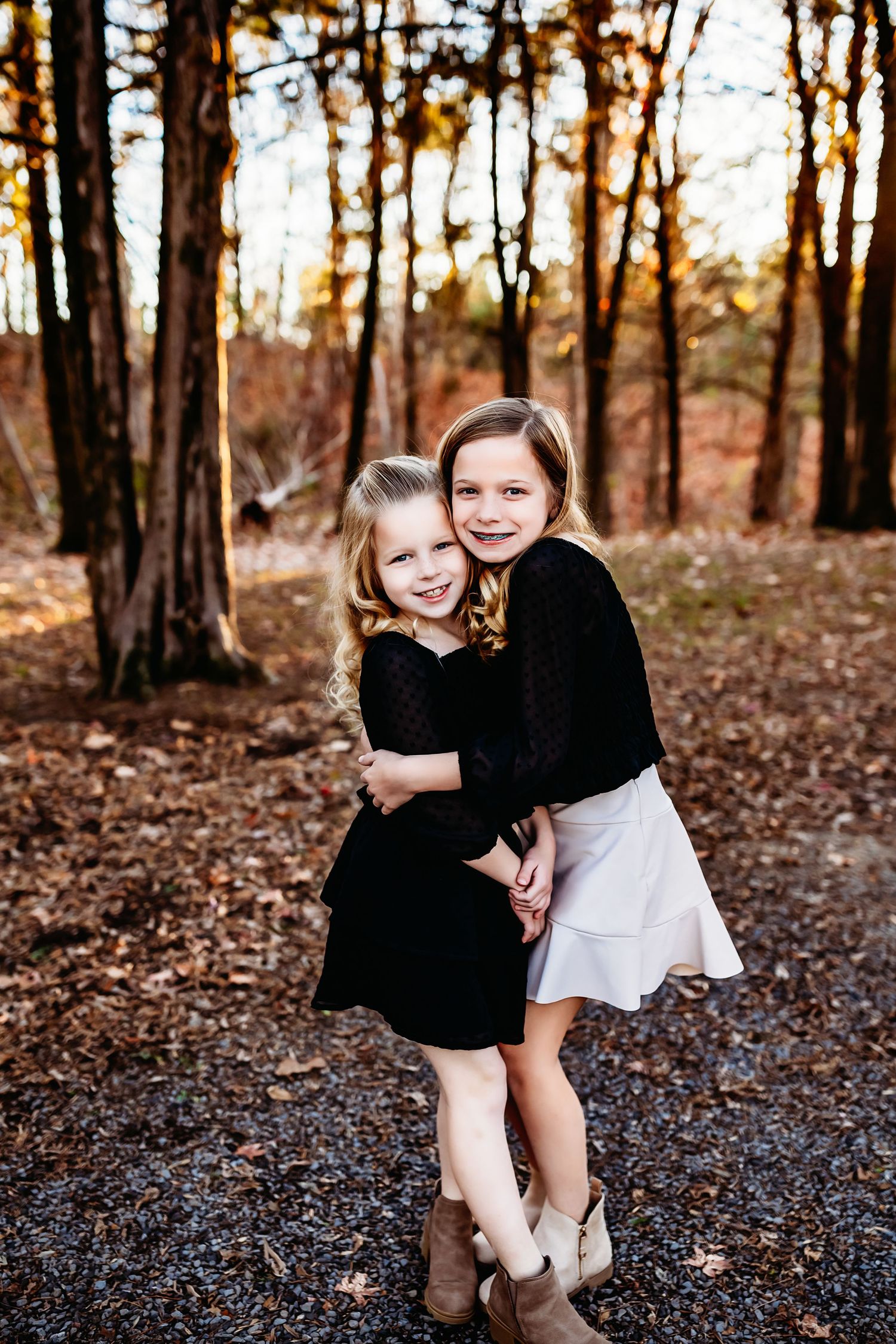 Two children hugging and laughing in an autumn forest setting.
