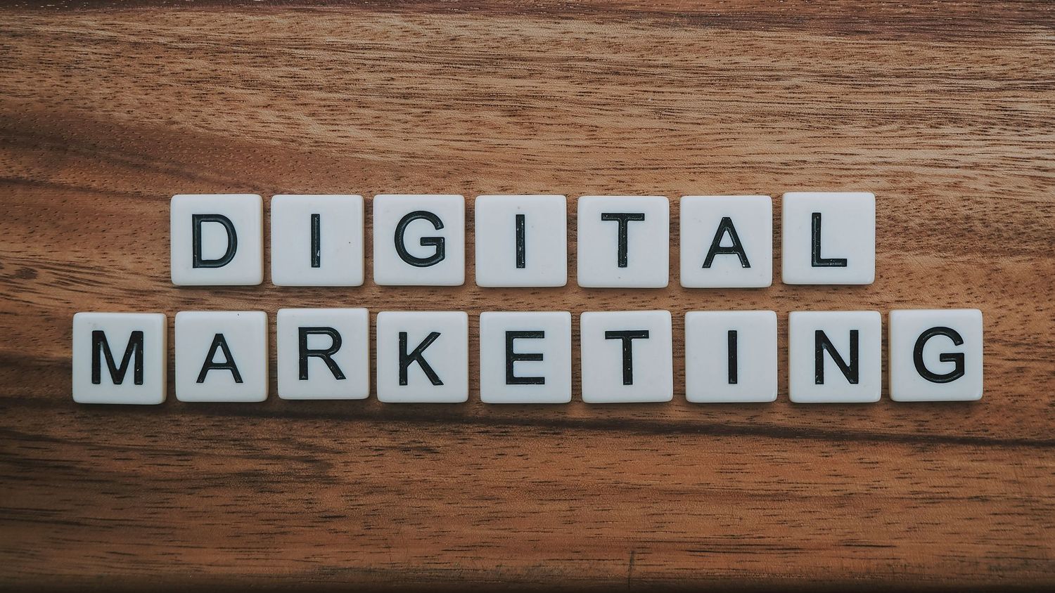 Scrabble tiles spelling DIGITAL MARKETING arranged on a wooden surface for SEO and online business concepts.