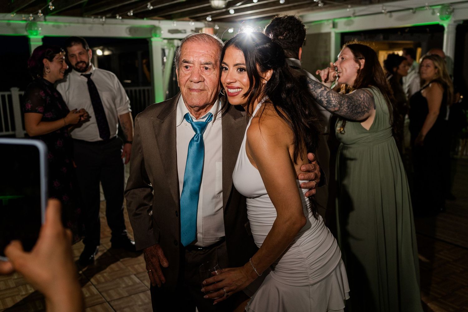 Bride and older gentleman smiling together at an outdoor wedding reception dance floor.