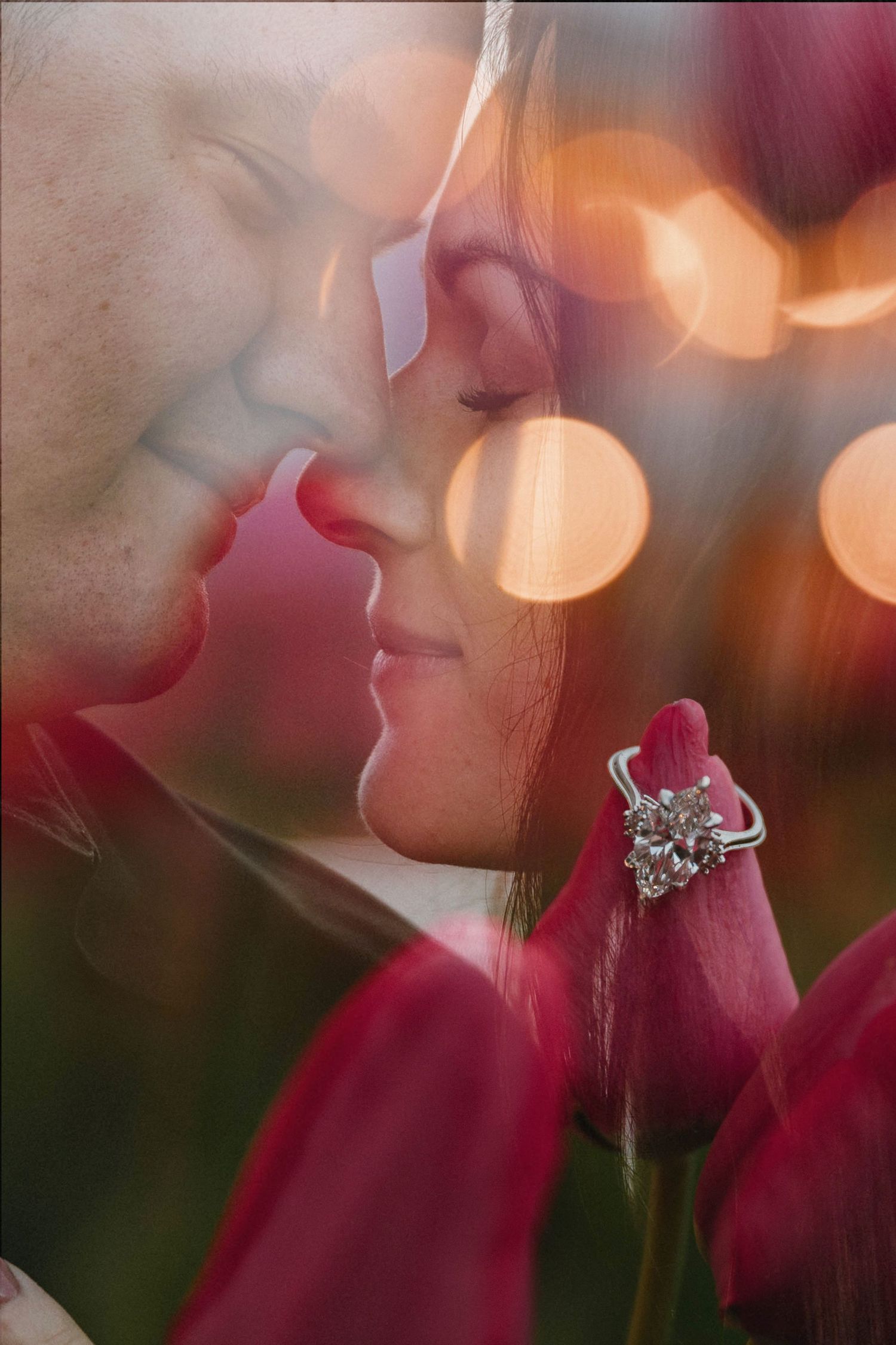 Romantic double exposure of couple almost kissing with diamond engagement ring on red tulip and bokeh lights.