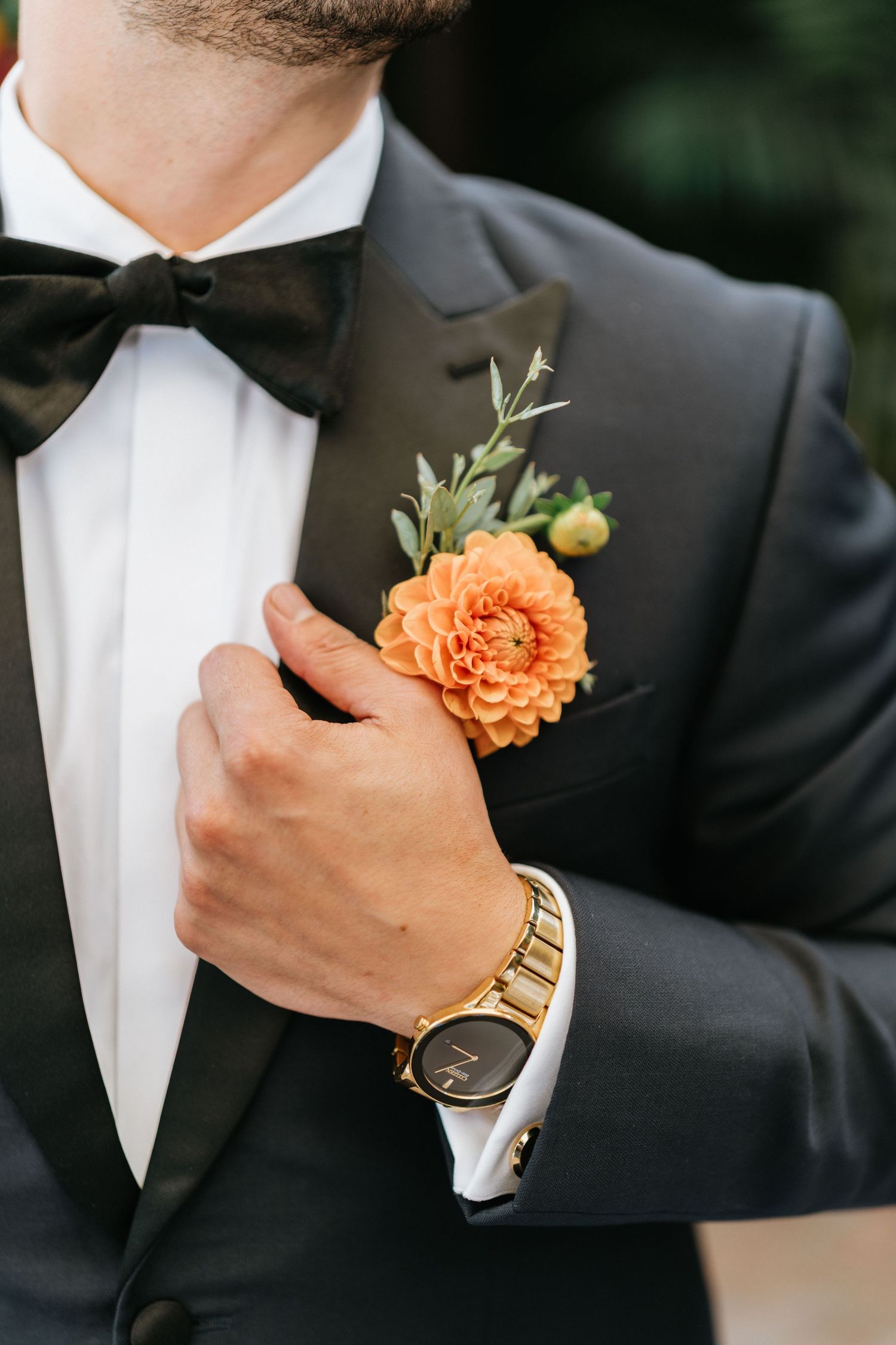 Close-up of the groom's orange boutonniere and tuxedo lapel before the ceremony.