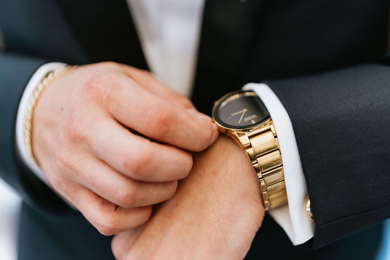 Close-up of the groom adjusting his gold wristwatch before the wedding ceremony.