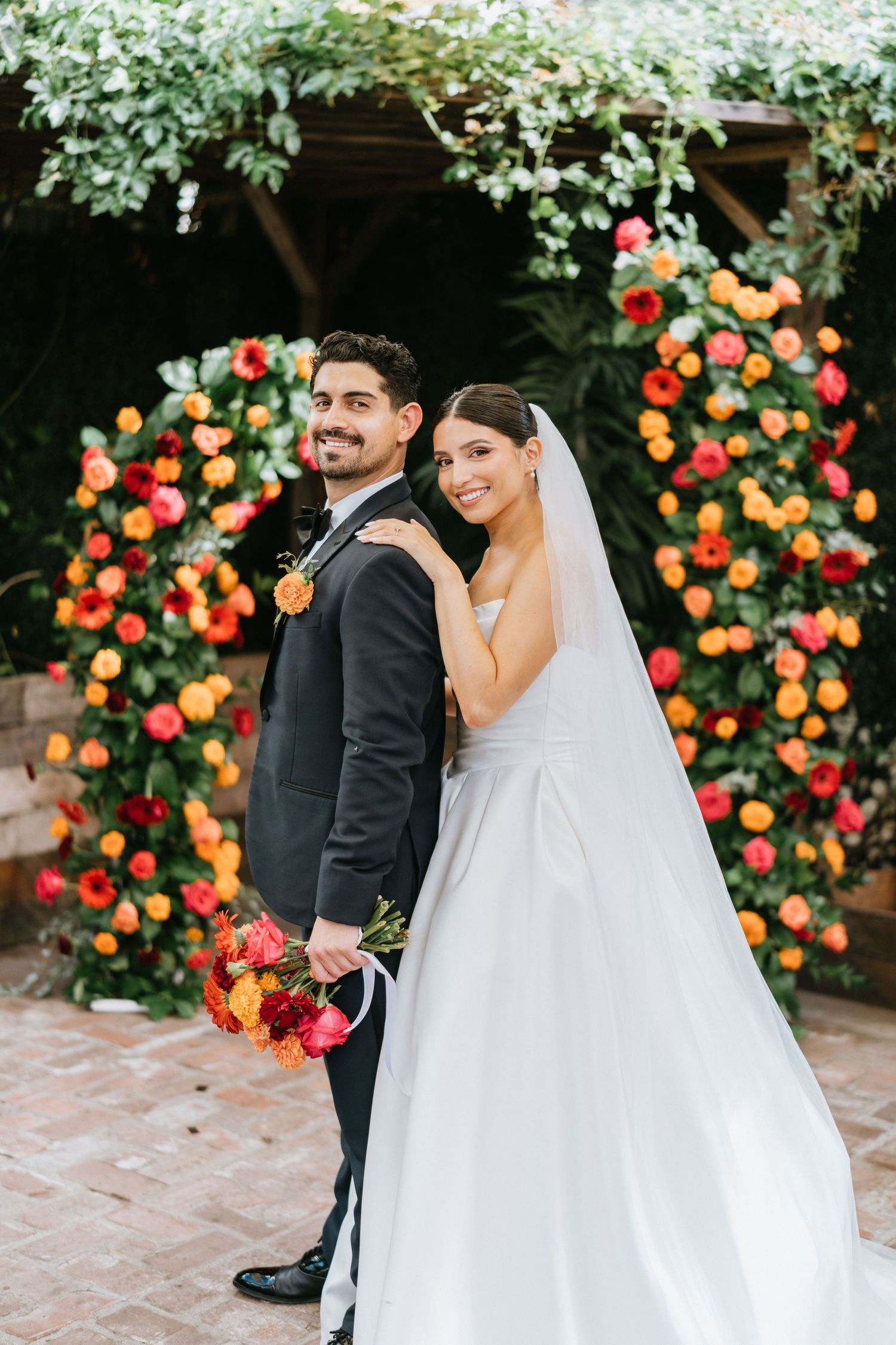 Portrait of Ruby and Sina together beneath the floral ceremony arch after exchanging vows.