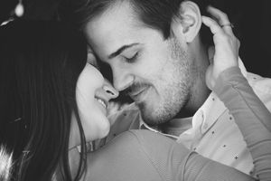 Black and white close-up of a smiling couple touching noses in an intimate romantic portrait.