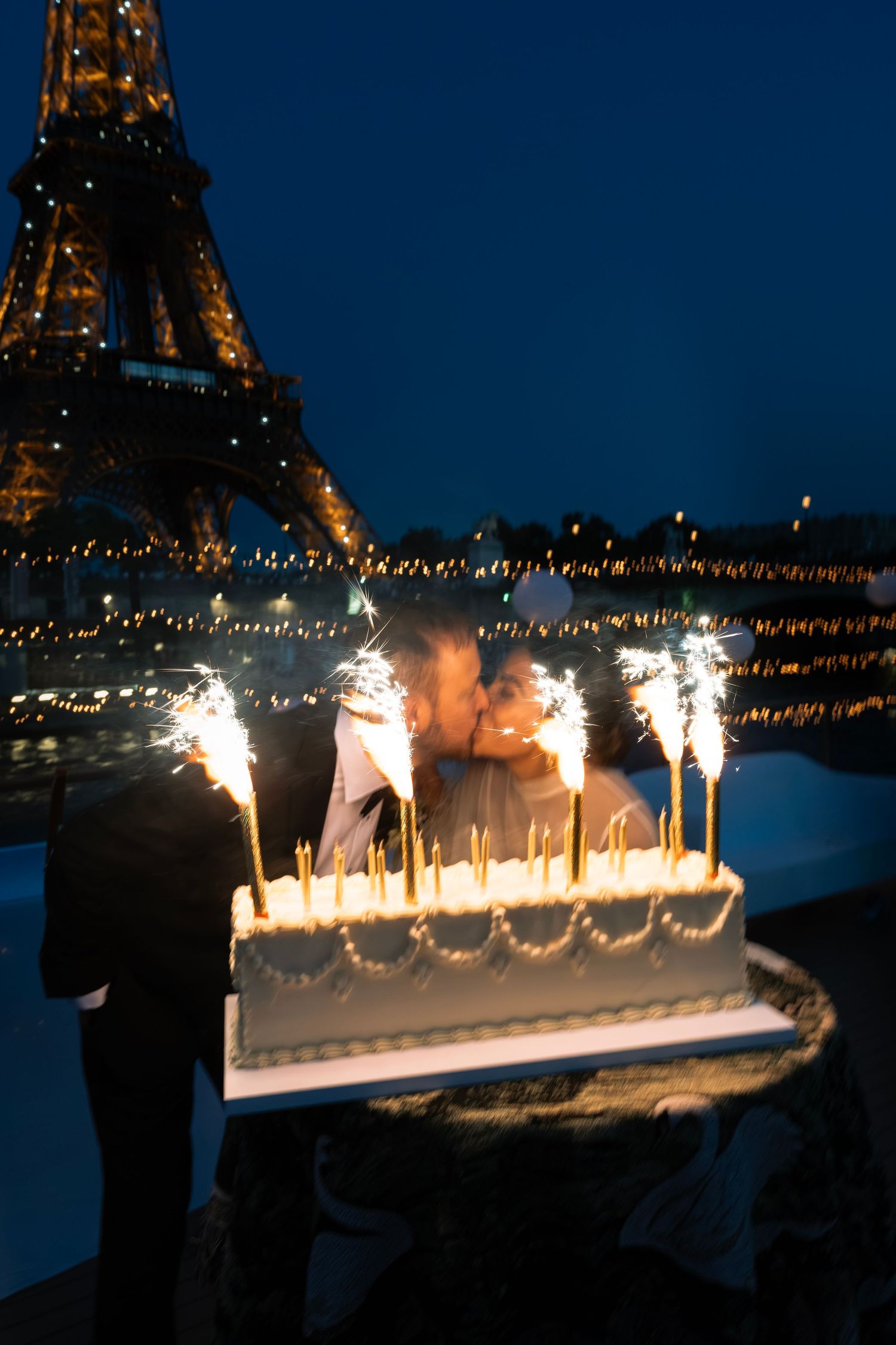 Couple kissing behind a wedding cake with sparklers near the Eiffel Tower at night in Paris. Paris night time wedding, Paris wedding photo