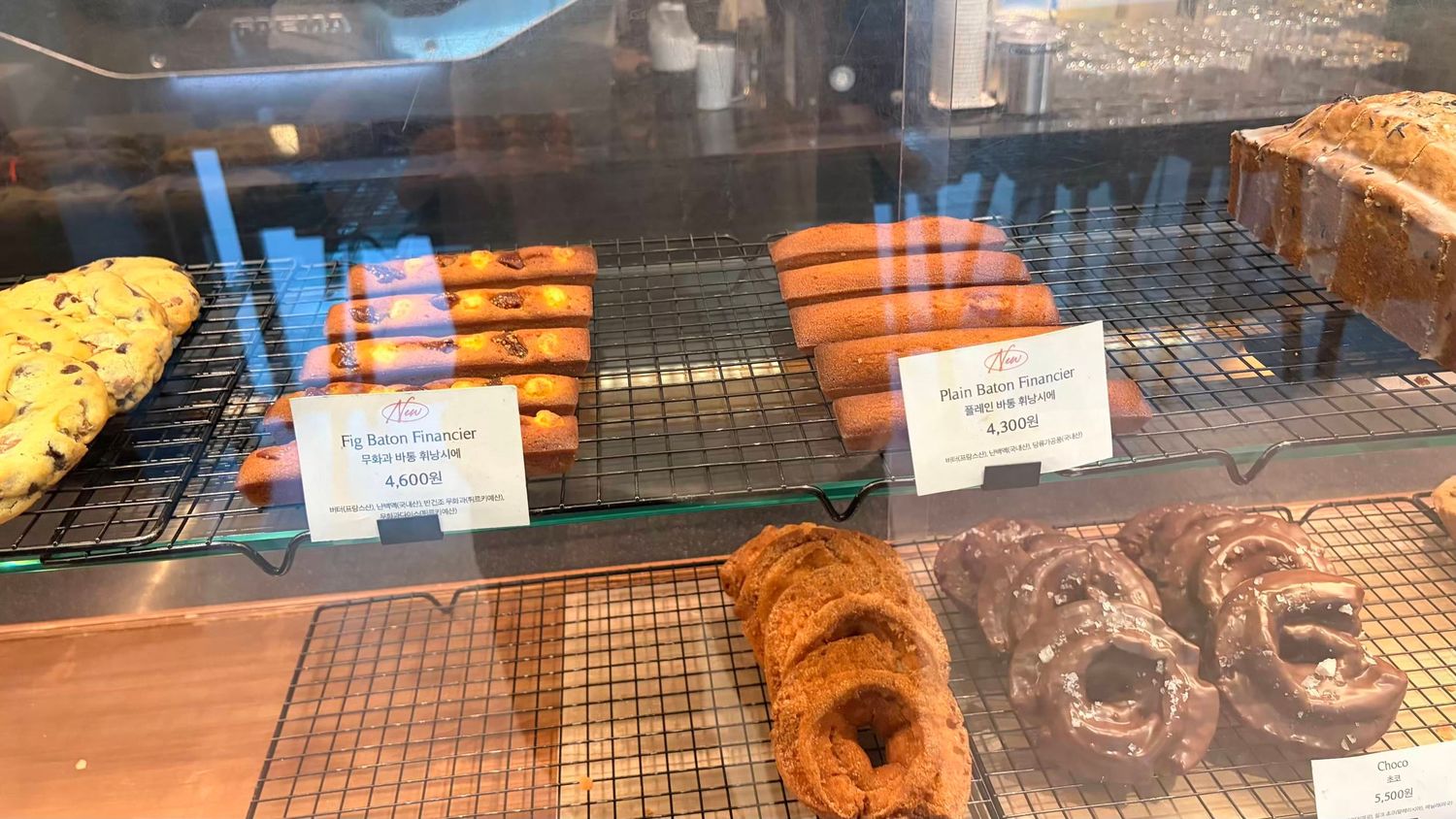 Freshly baked pretzels and pretzel cake displayed on wire racks inside a bakery glass case.