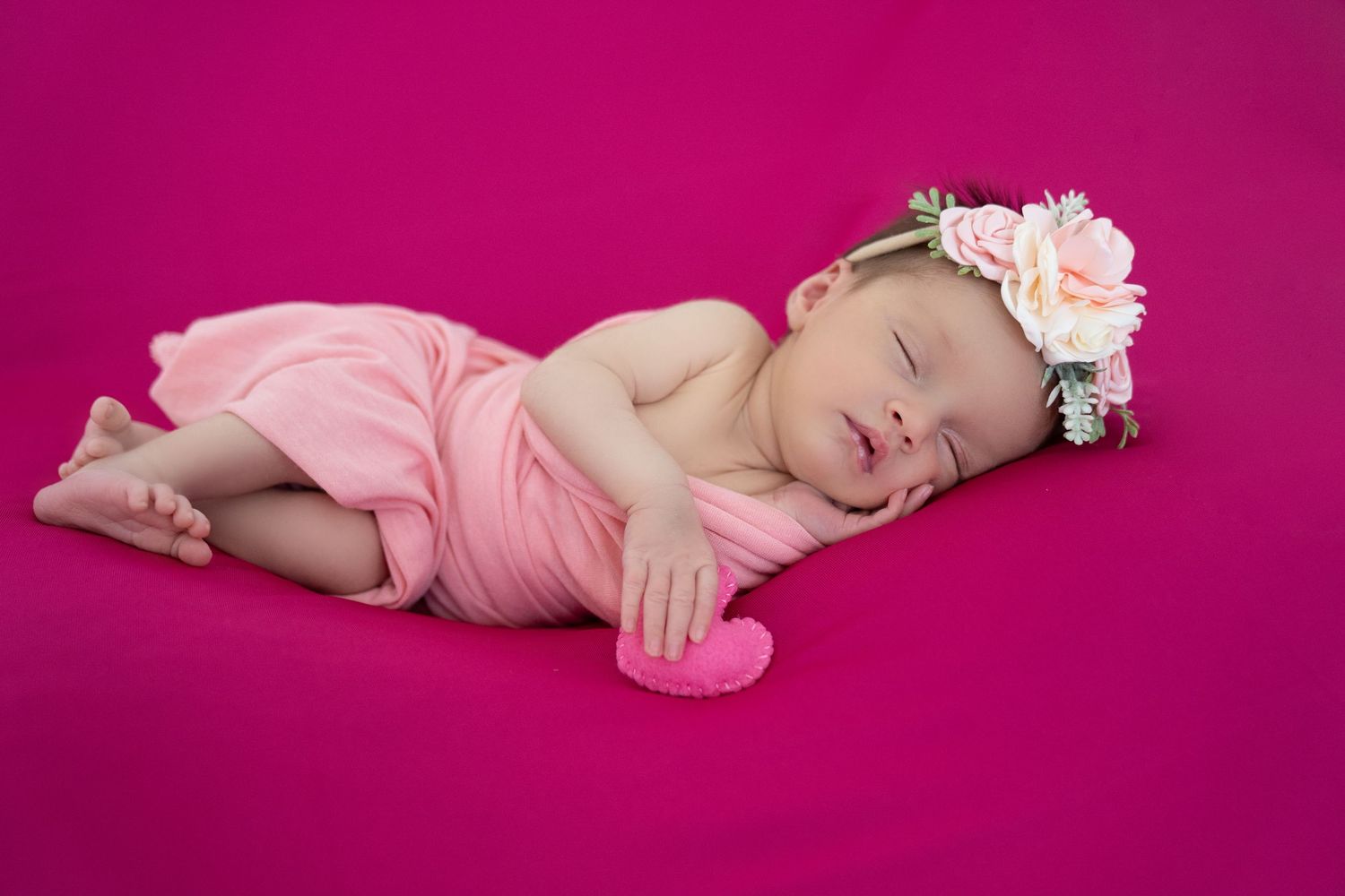 Newborn baby swaddled in gray wrap posed with Harry Potter scarf, wand, book, and plush doll prop.