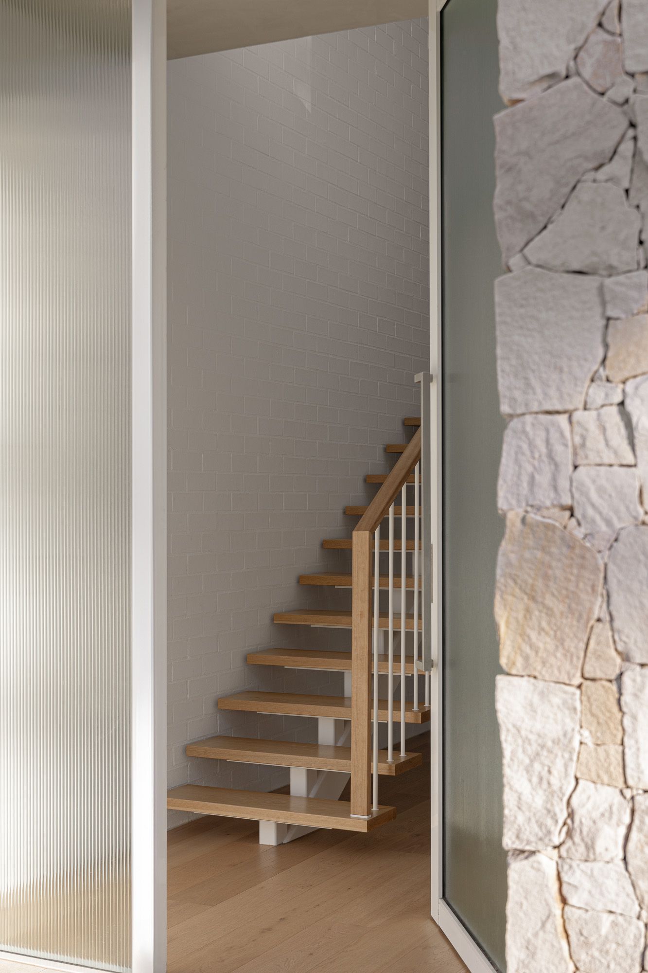 Interior architectural photography of a timber staircase and natural stone wall captured in Port Hacking, Sutherland Shire NSW.