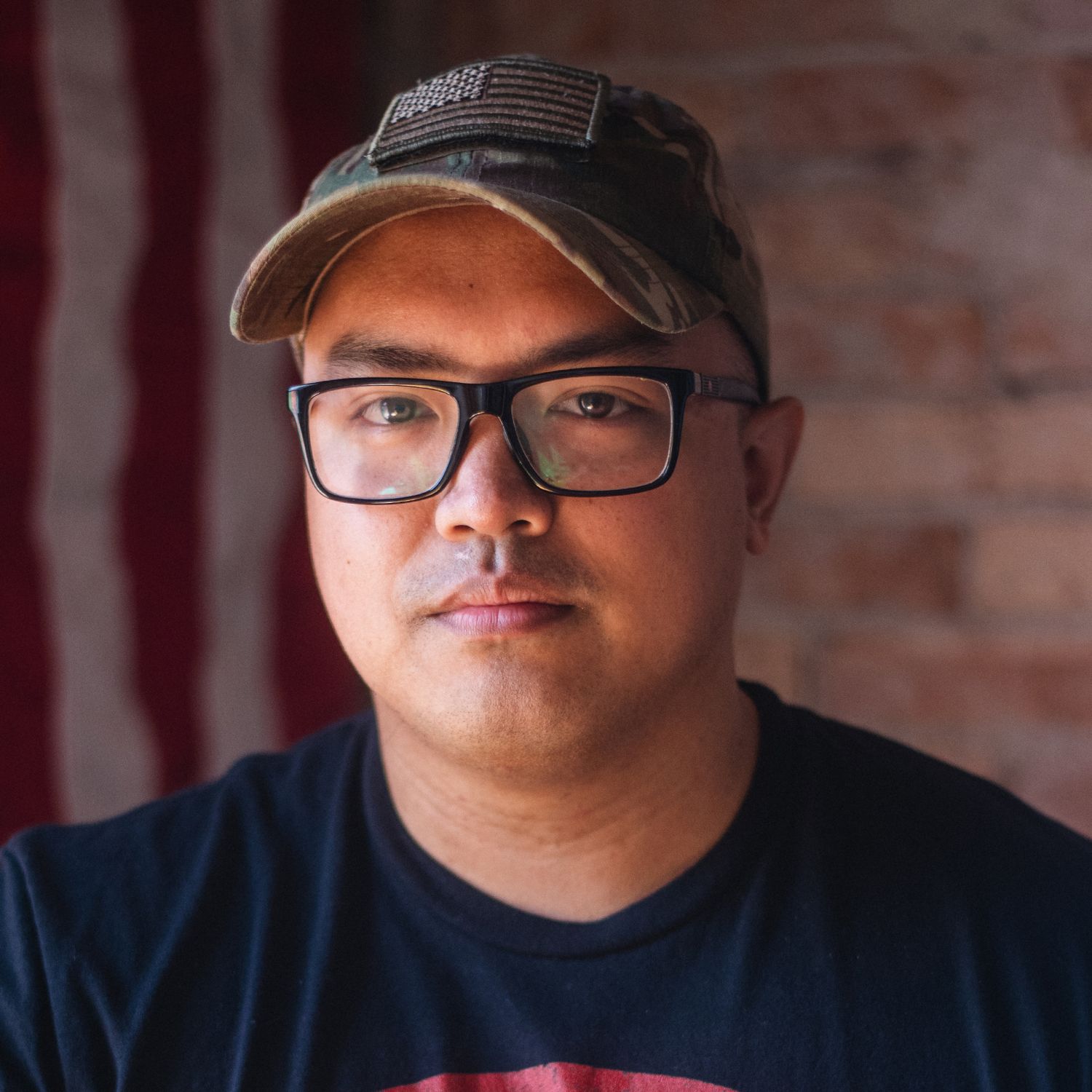 Orlando actor headshot photographer Ray Alvarez — male talent environmental headshot with glasses and brick background