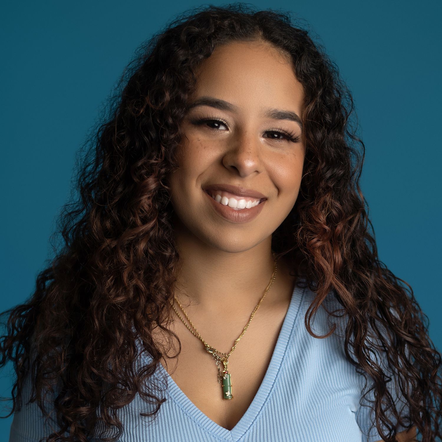 Orlando actress headshot photographer Ray Alvarez — female talent headshot with blue background and natural curly hair
