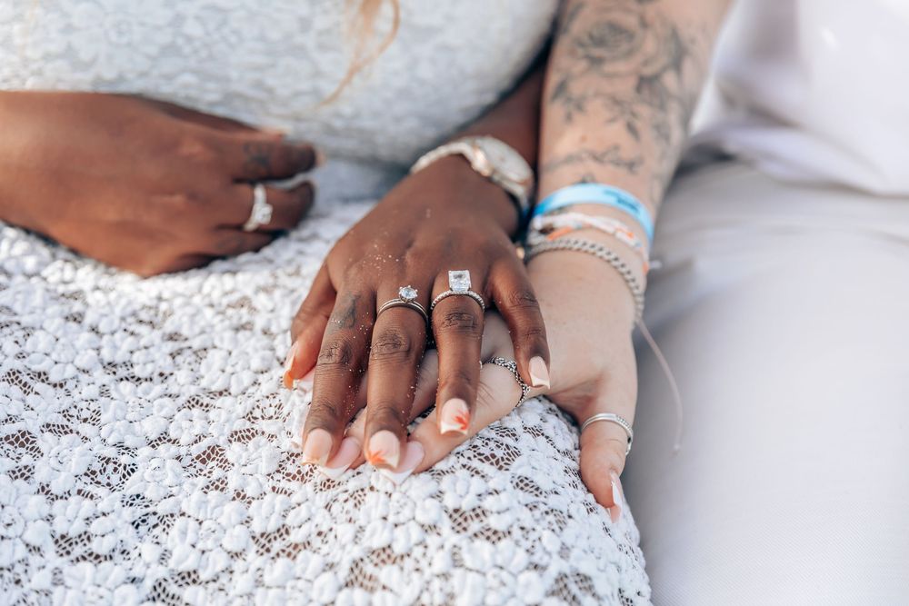 Close-up of two women holding hands, beautifully showcasing their diamond engagement rings during a surprise proposal photoshoot in Mallorca