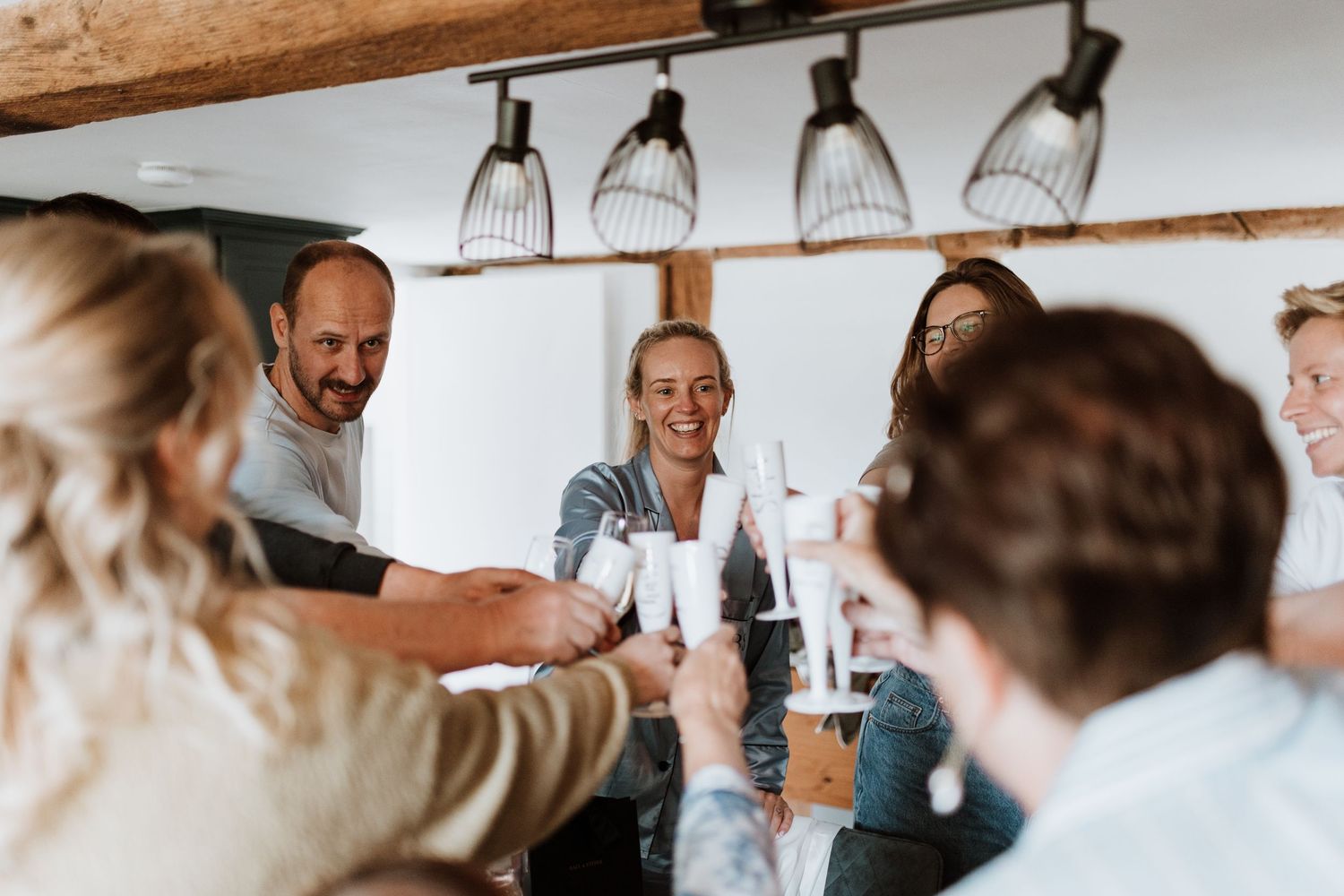 Group of friends toasting with champagne glasses indoors, smiling and celebrating together at stanford farm