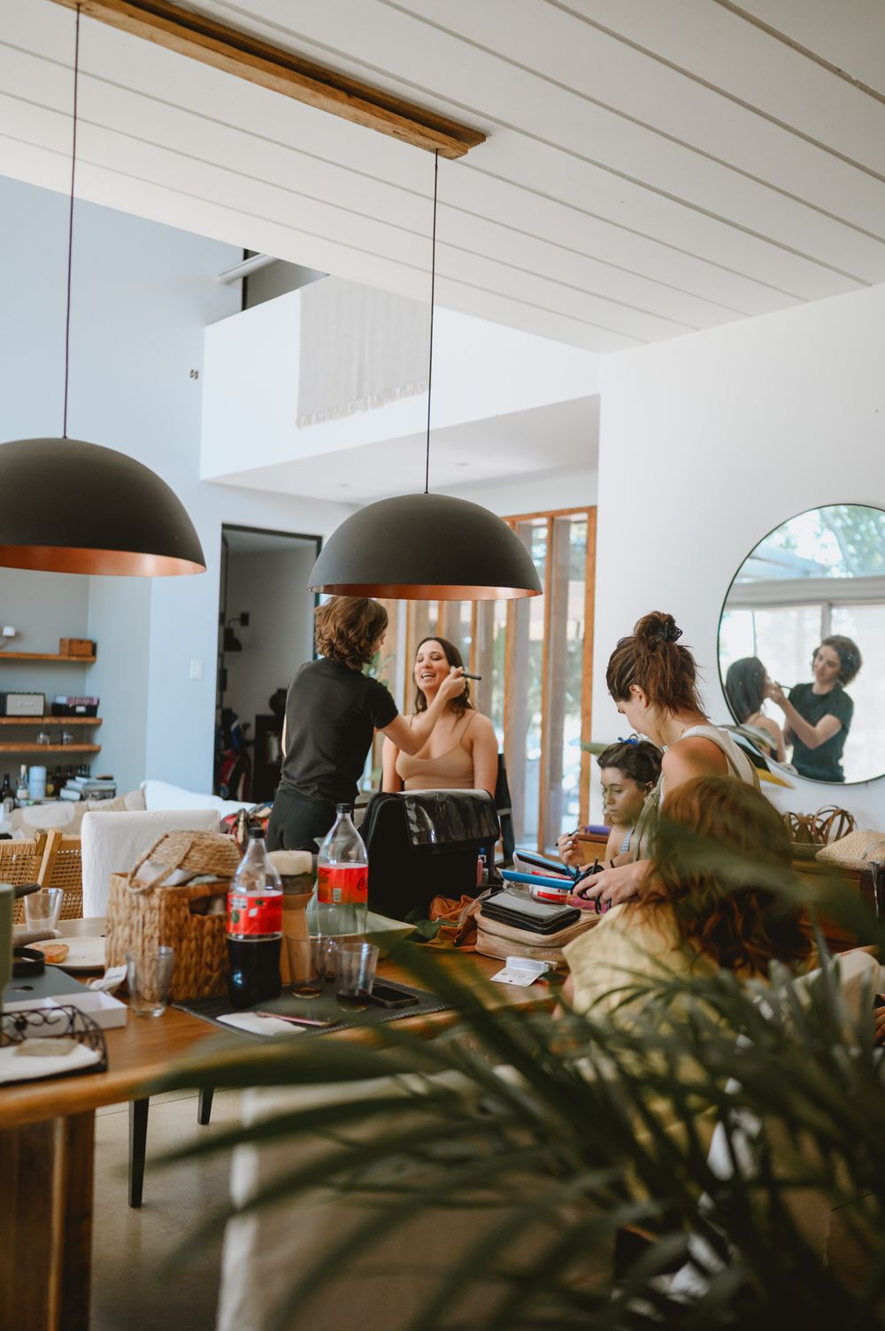 Bride getting makeup done in a bright modern home during wedding day preparations.