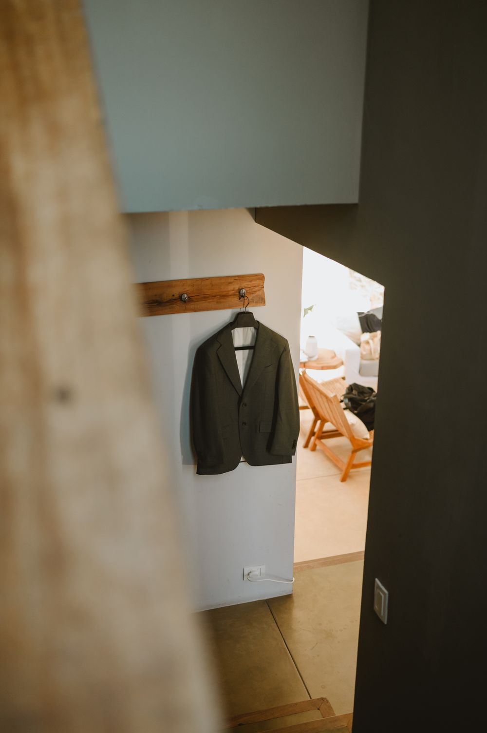 Dark suit jacket hanging on wall hook in a softly lit modern hallway interior.