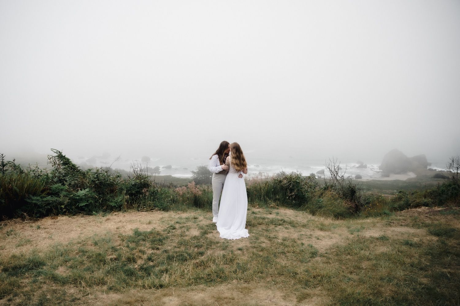 A foggy coastal shot of a beautiful lesbian couple eloping on the southern oregon coast