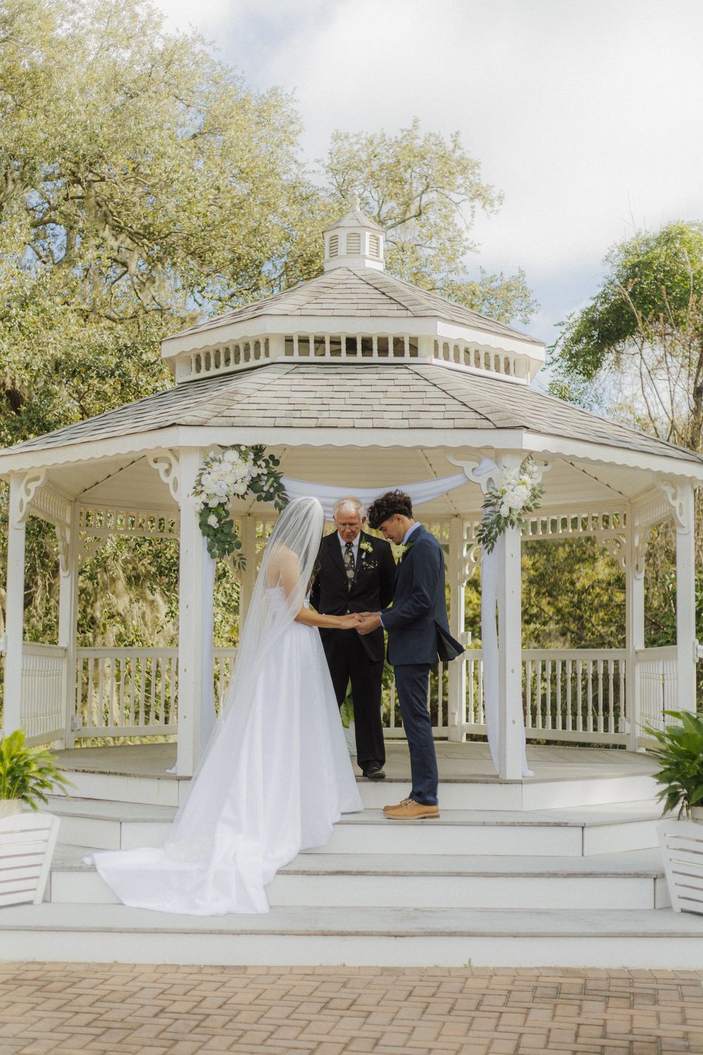 A white wedding gazebo ceremony setup with elegant decor and natural surroundings.