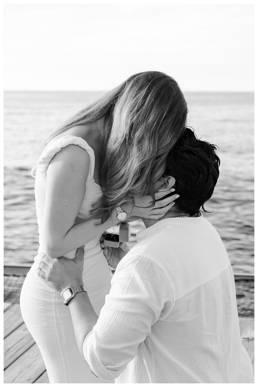 One and Only Mandarina engagement photographer capturing couple kissing on a dock in a black and white photo.