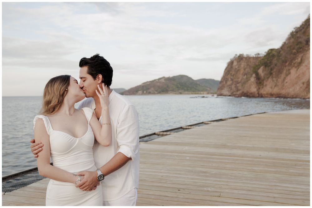 One and Only Mandarina engagement photographer capturing a couple sharing a romantic kiss on a wooden pier with beach engagement photos.