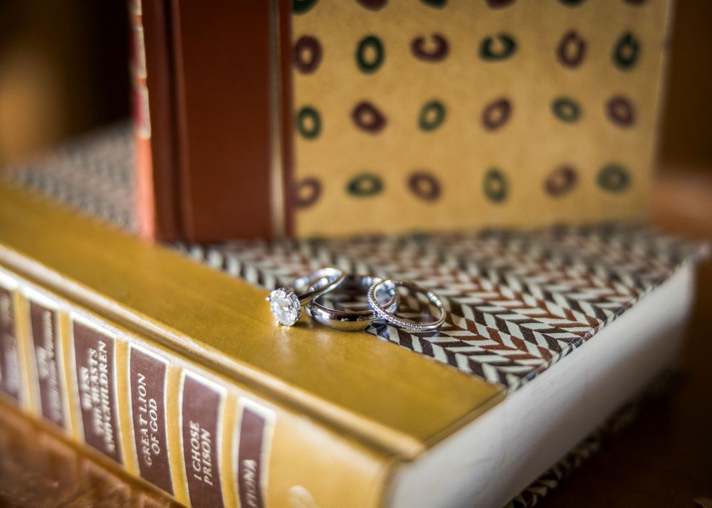 Diamond wedding rings and earrings displayed on vintage hardcover books, elegant jewelry detail shot.