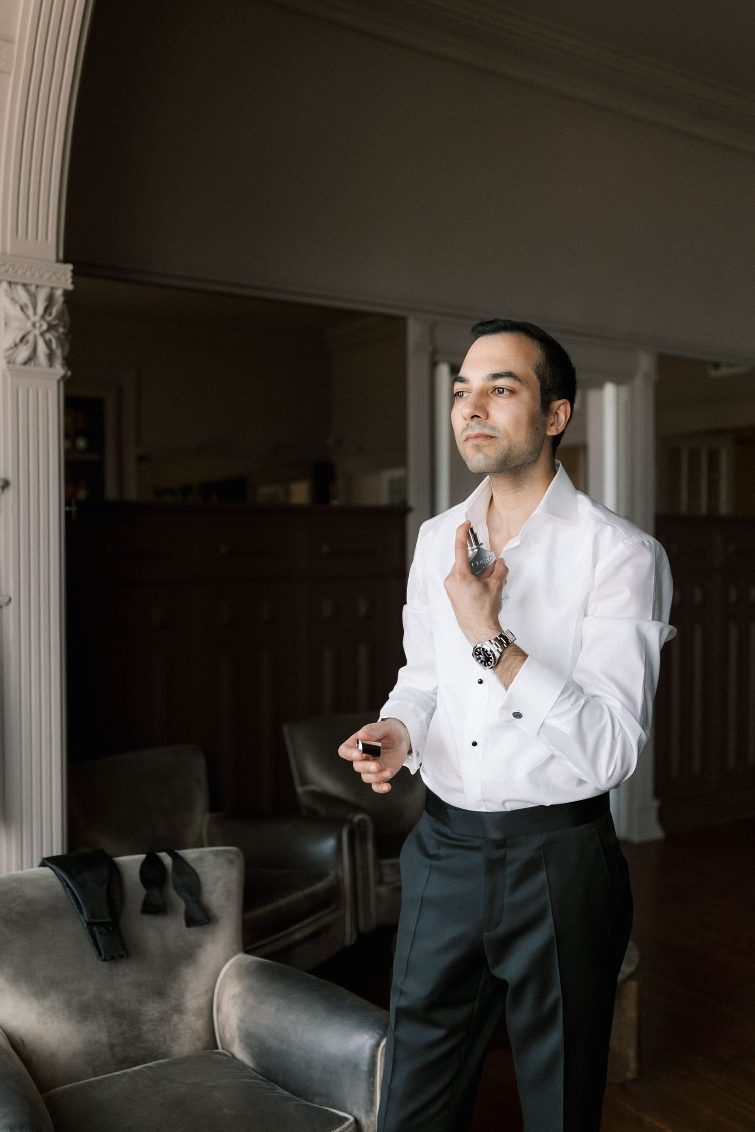 Groom adjusting his bow tie during wedding preparations at Farol Hotel before the ceremony overlooking the Atlantic.