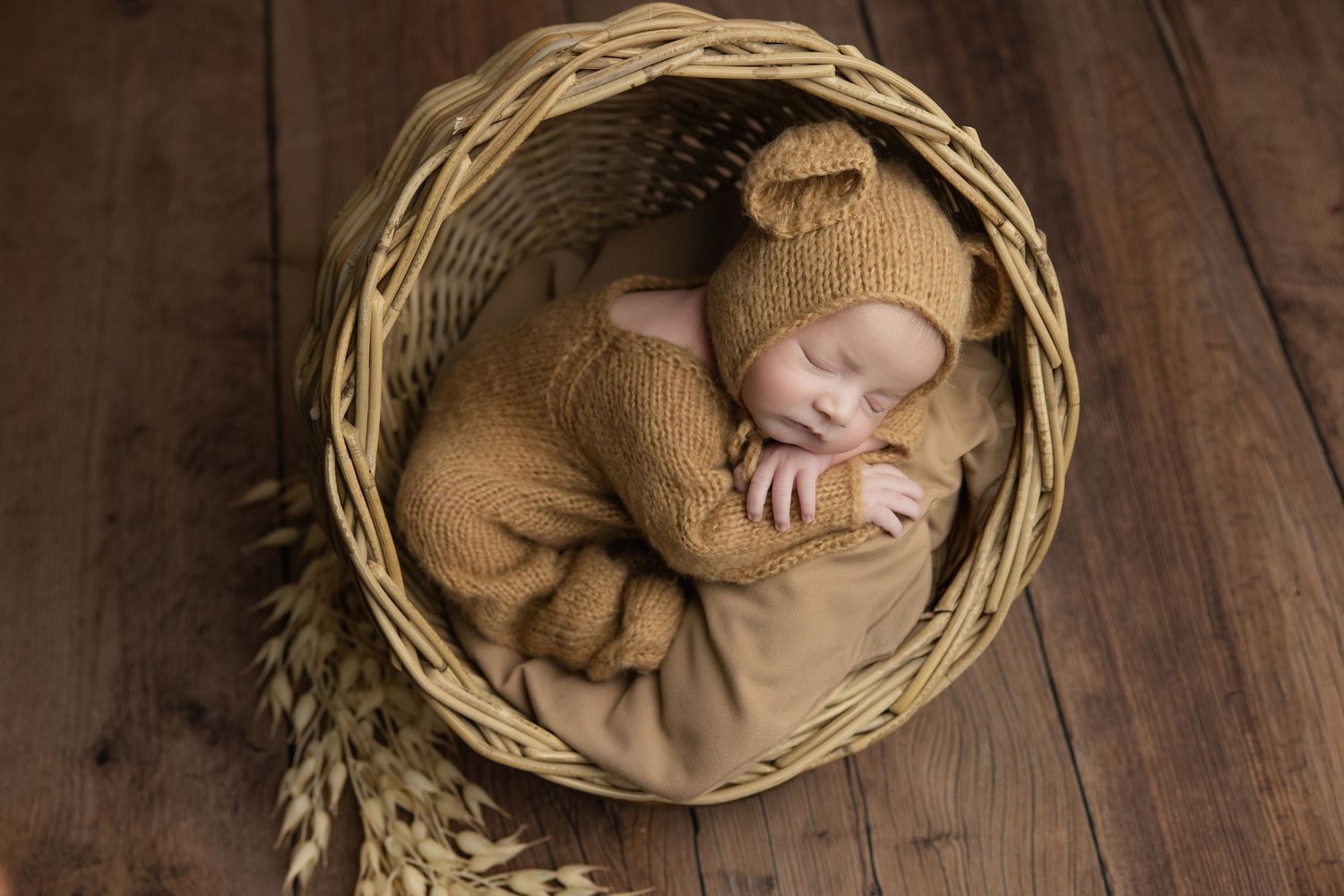 Newborn baby in teal hooded knit onesie with wooden buttons, sitting in a vintage metal bucket with soft teal blankets.