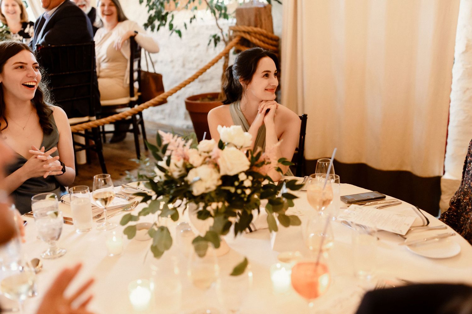 Elegant wedding reception table setting with white floral centerpieces and candlelight.