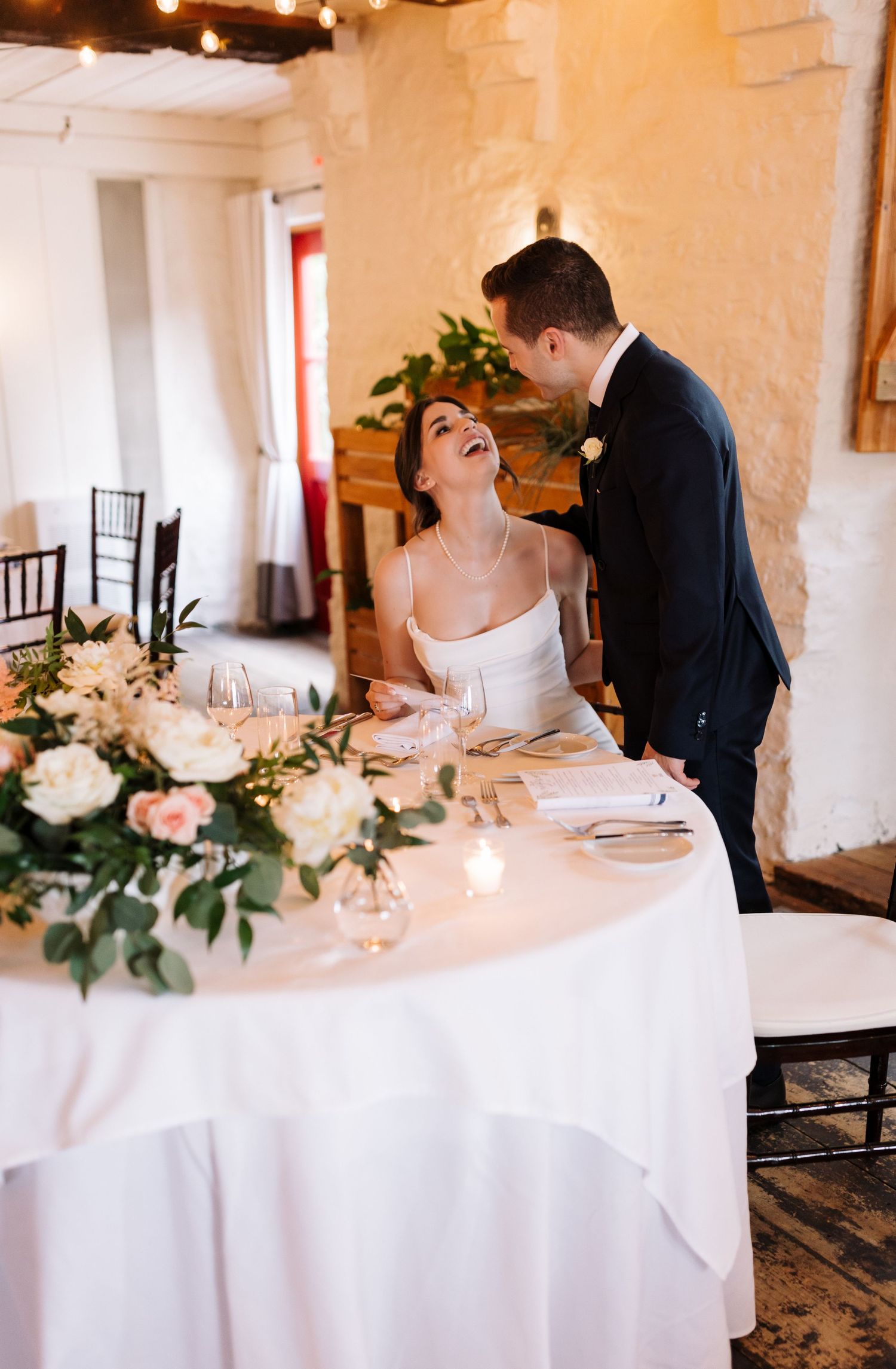A couple shares a joyful moment at an elegant table setting with floral decor.