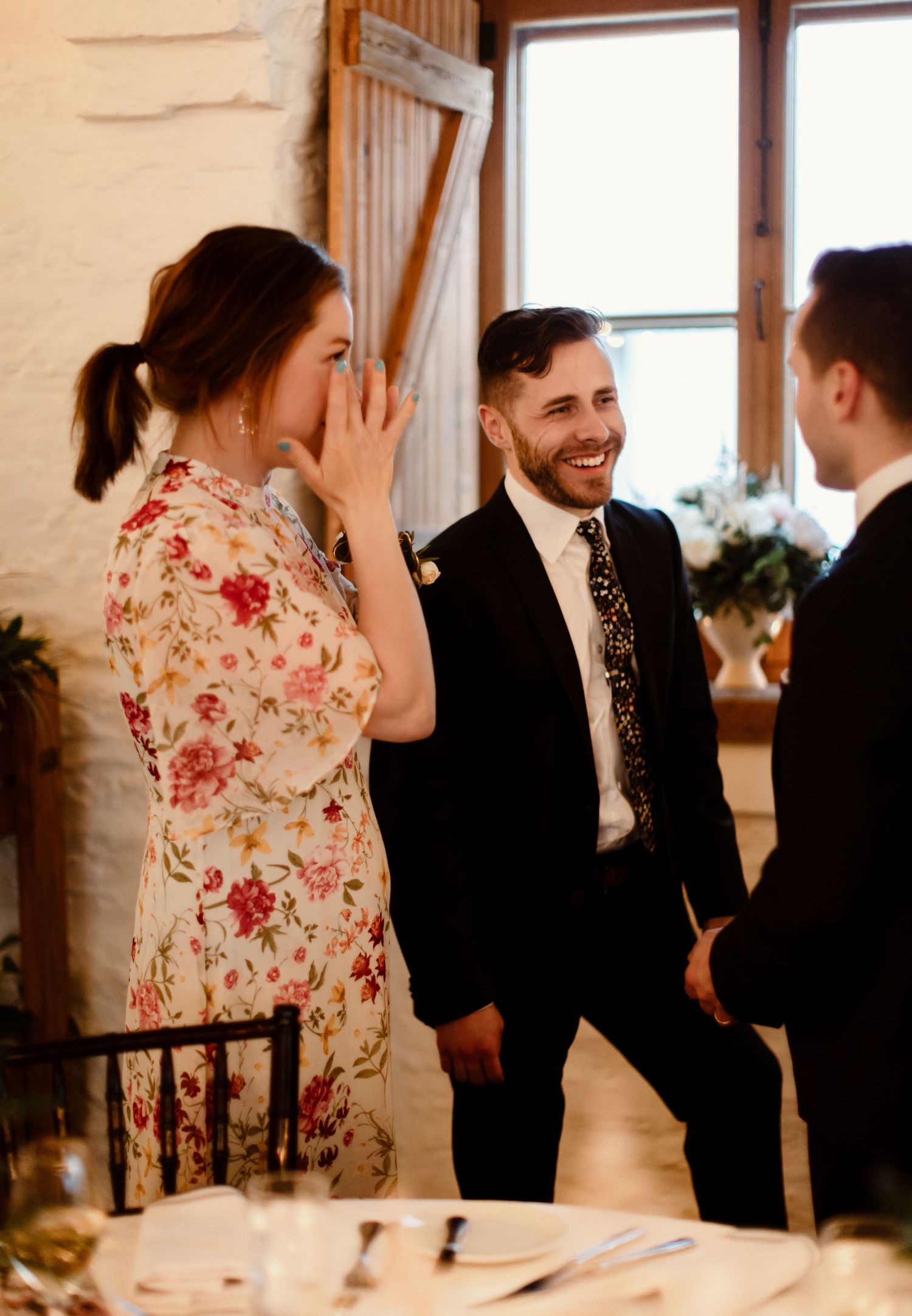 Wedding guests share a happy moment during a reception in a rustic venue.