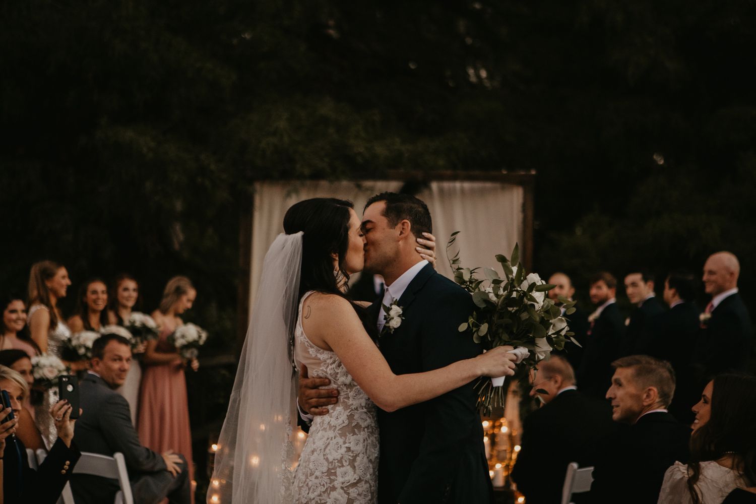 A wedding couple shares their first dance surrounded by guests at an outdoor ceremony.