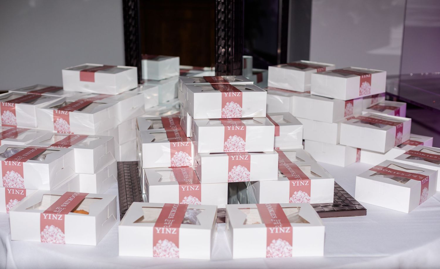 Multiple white favor boxes with red ribbons arranged in neat rows on a table.