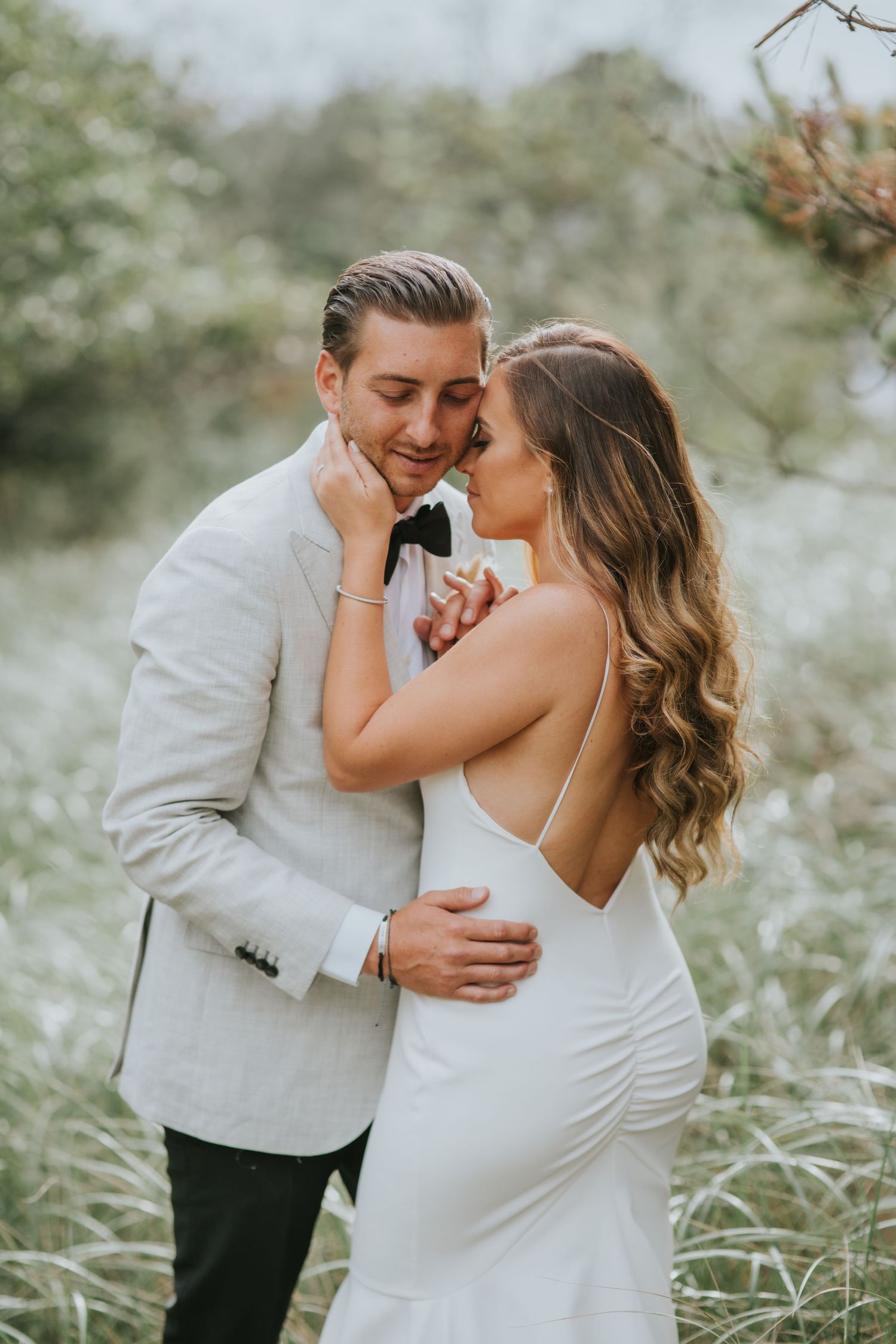 Romantic moment between a couple in formal attire embracing in a dreamy outdoor garden setting.
