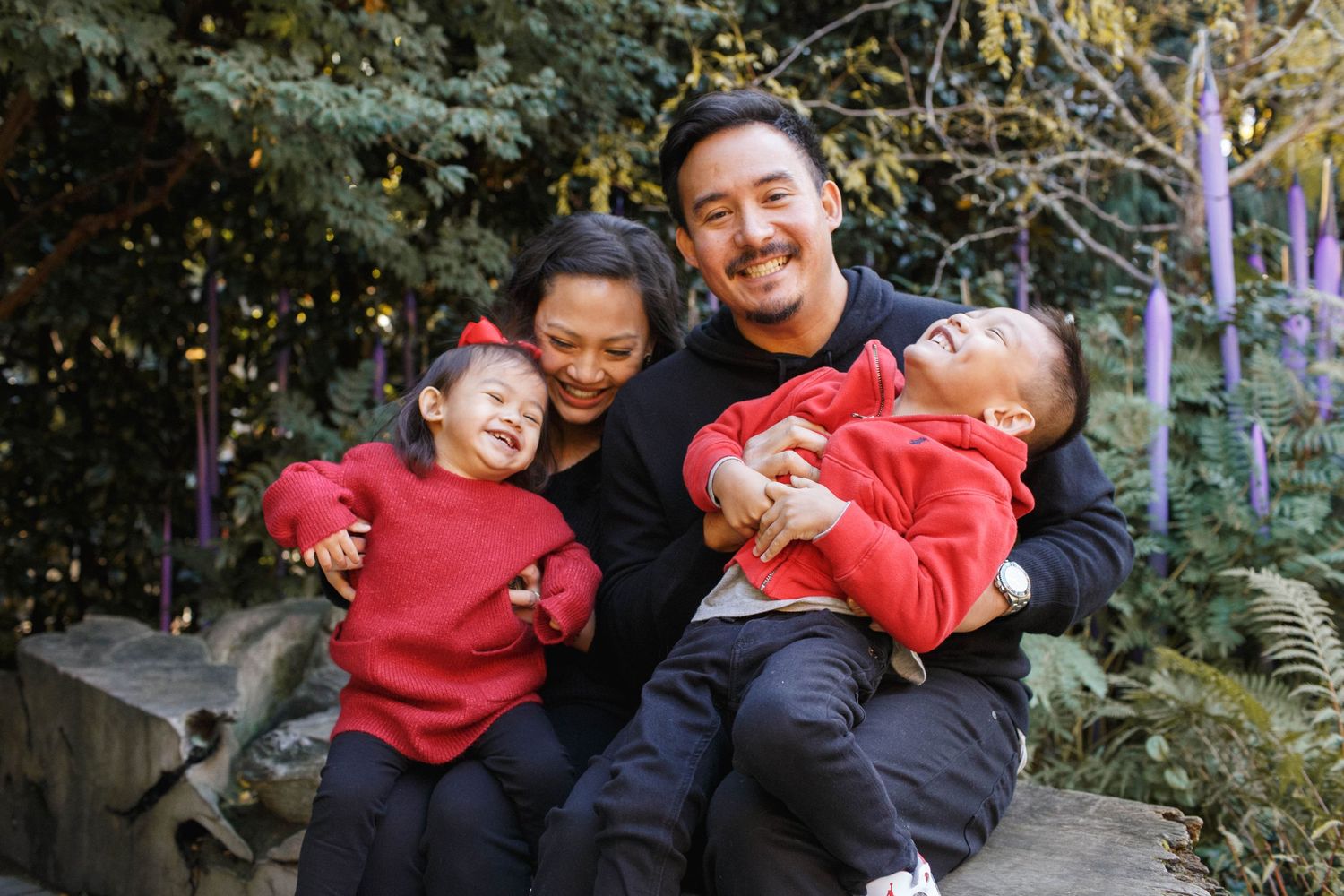 Chihuly family photos: a family of four sitting in the garden at the chihuly garden and glass museum in seattle