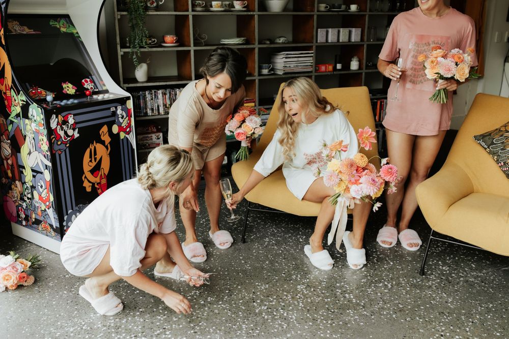 Casual gathering scene with people holding floral bouquets in relaxed indoor setting.