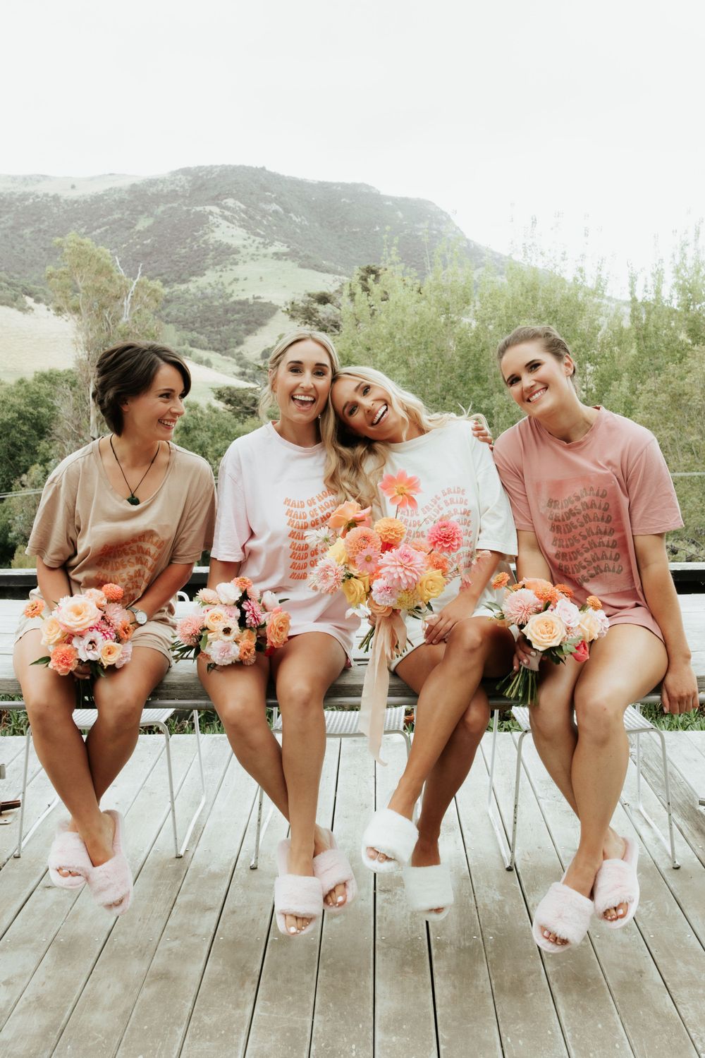Group in coordinated outfits sitting with flowers on outdoor deck with mountain view.