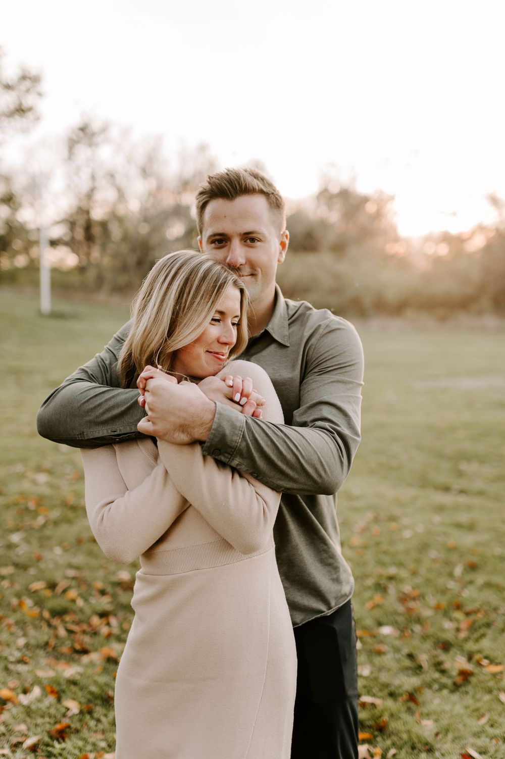 Couple sharing joyful embrace in autumn field during sunset.