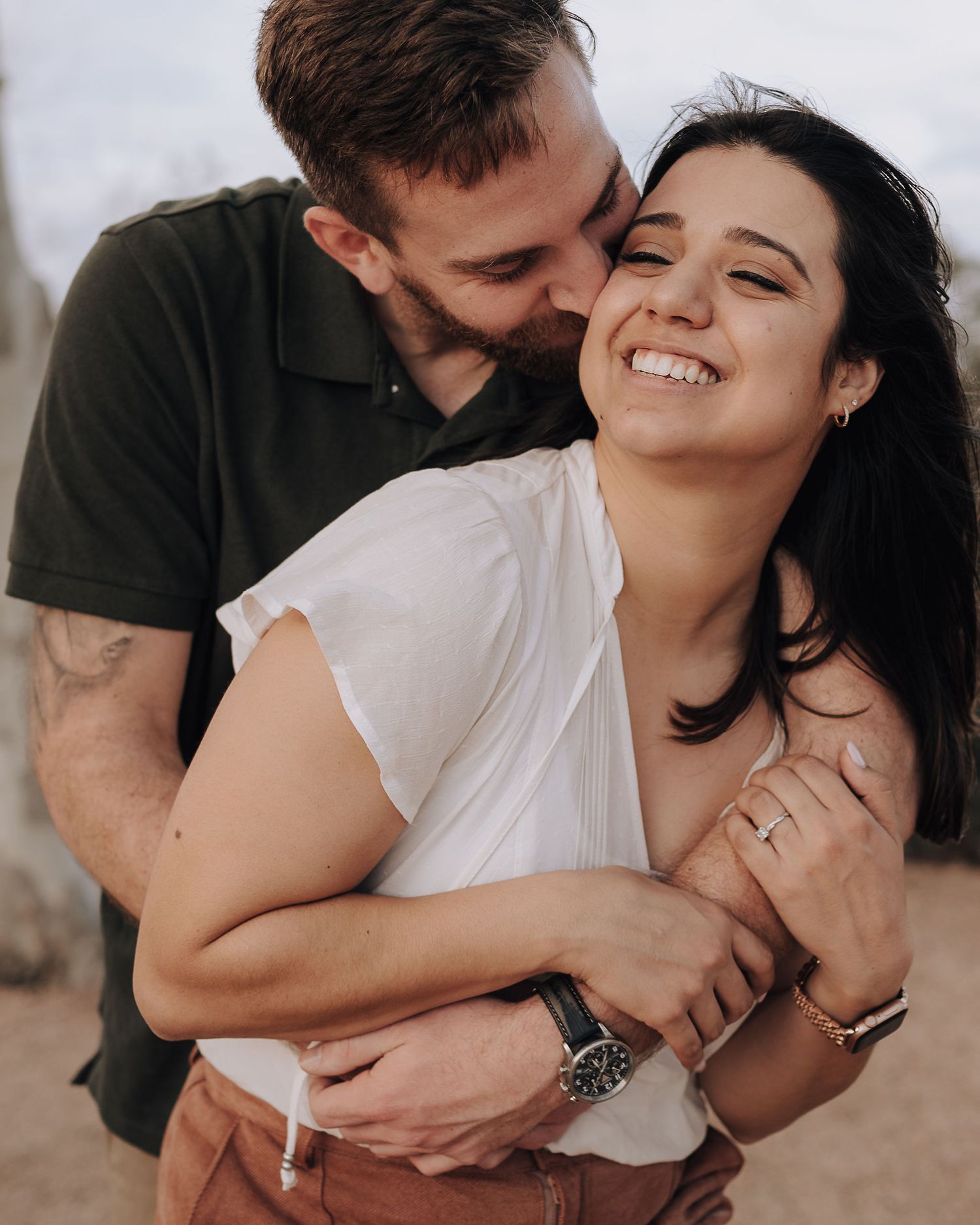 A candid moment of joy and laughter between a couple embracing outdoors.