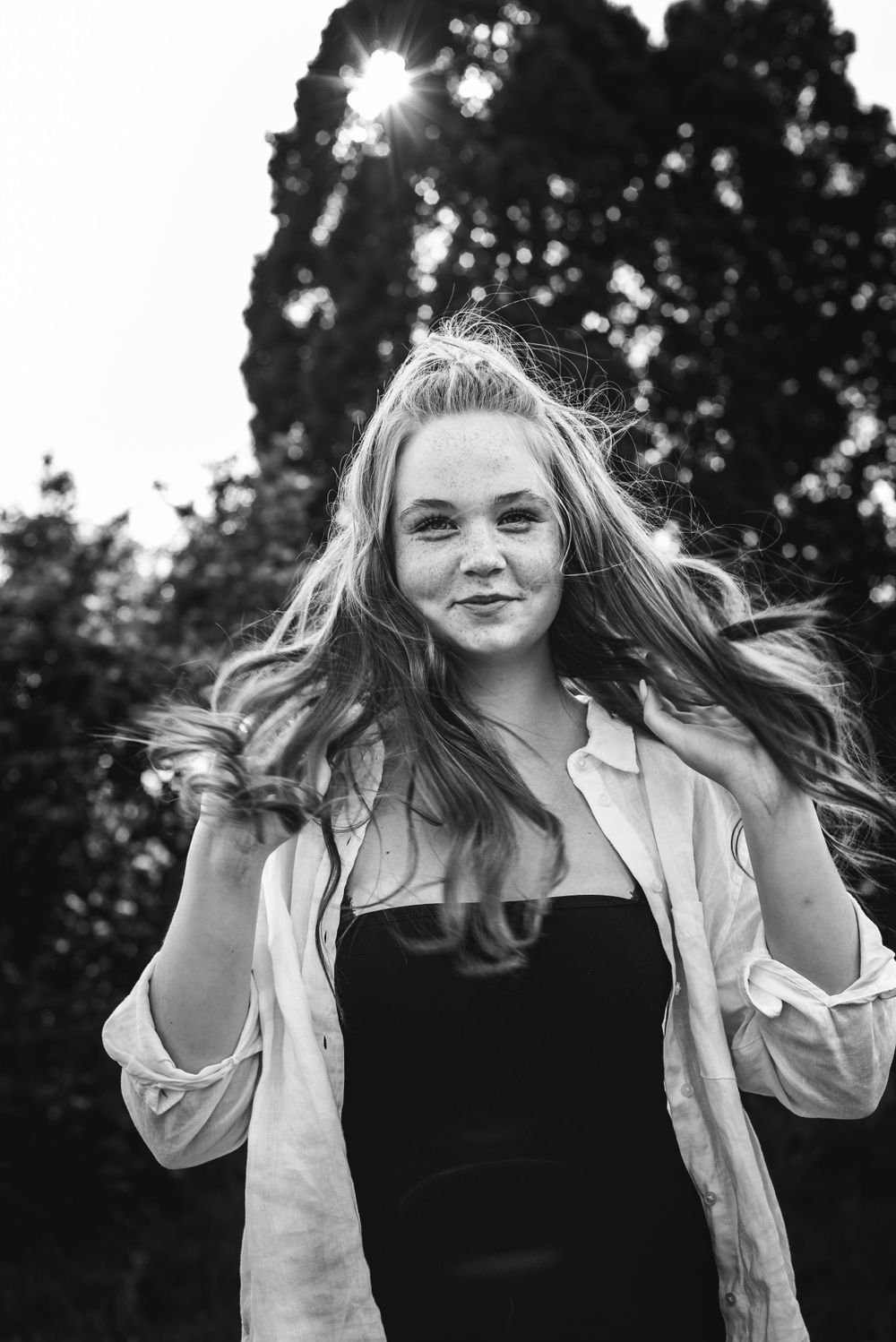 BW image of a teenage girl with long hair and the sun going down behind her.