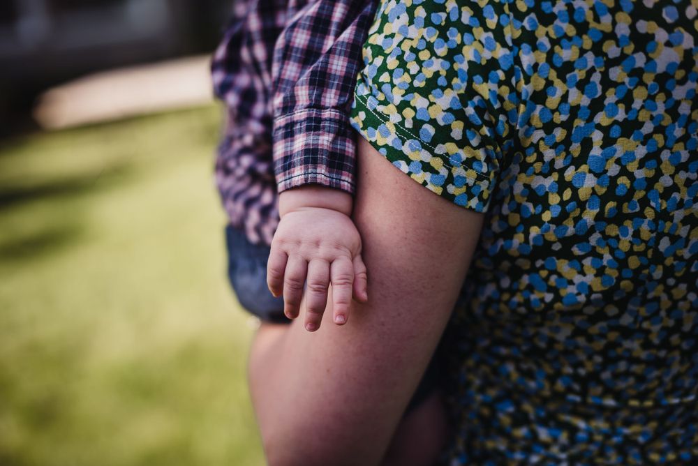 Close up of a baby's hand on his mother's arm.