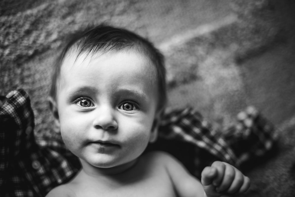 BW image of a baby boy looking directly up at the camera