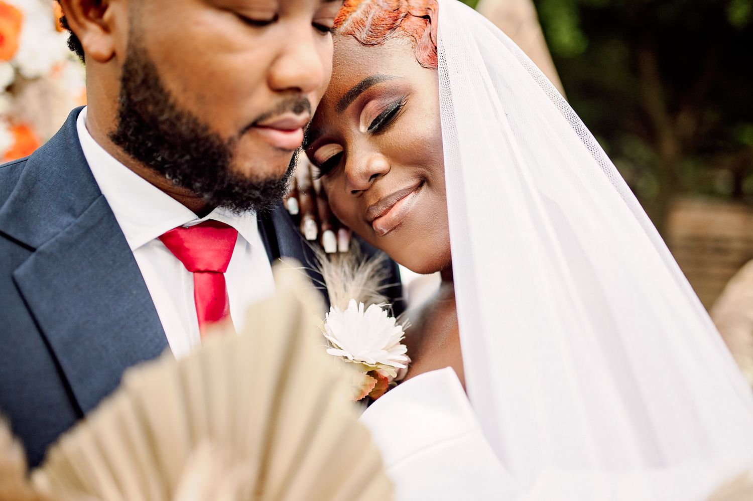 Intimate wedding portrait with decorative fan and white veil detail.