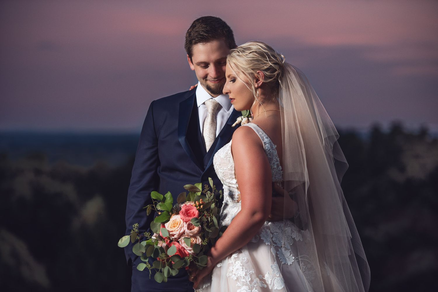 Romantic sunset wedding portraits with soft pink sky in the background.