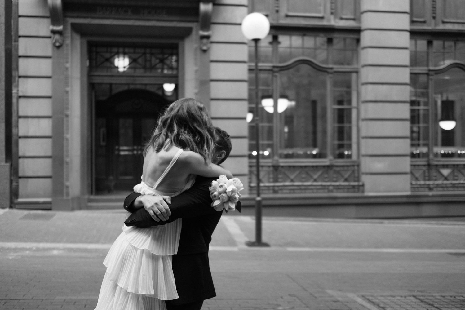 Bride and groom hugging tightly in front of a Sydney building.