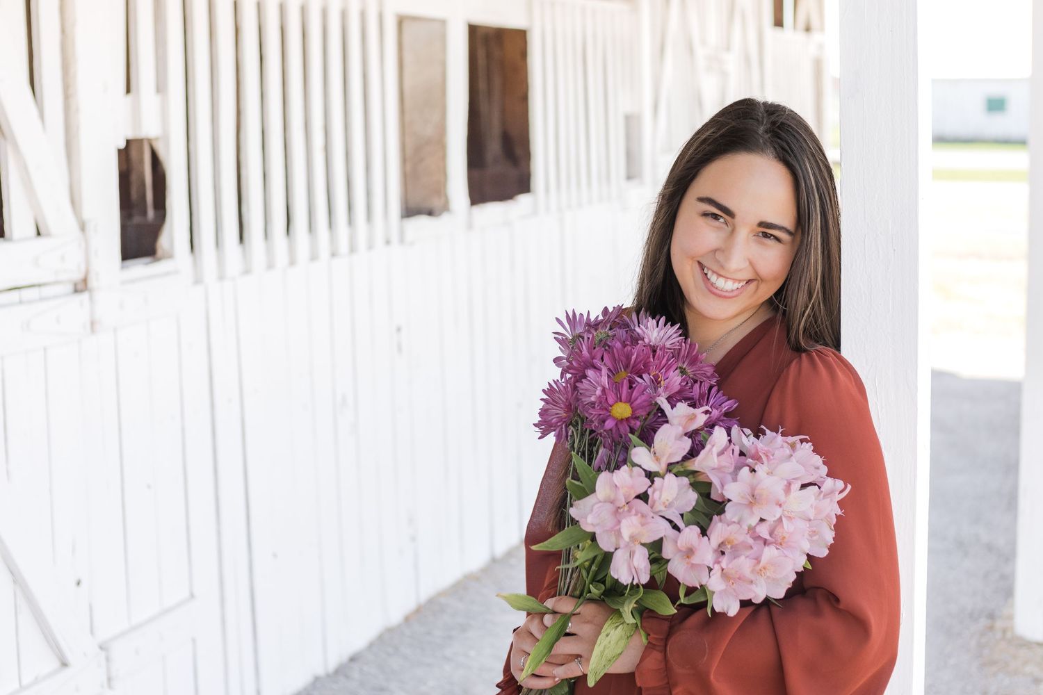 Senior Session with a beautiful girl holding flowers and smiling at the camera