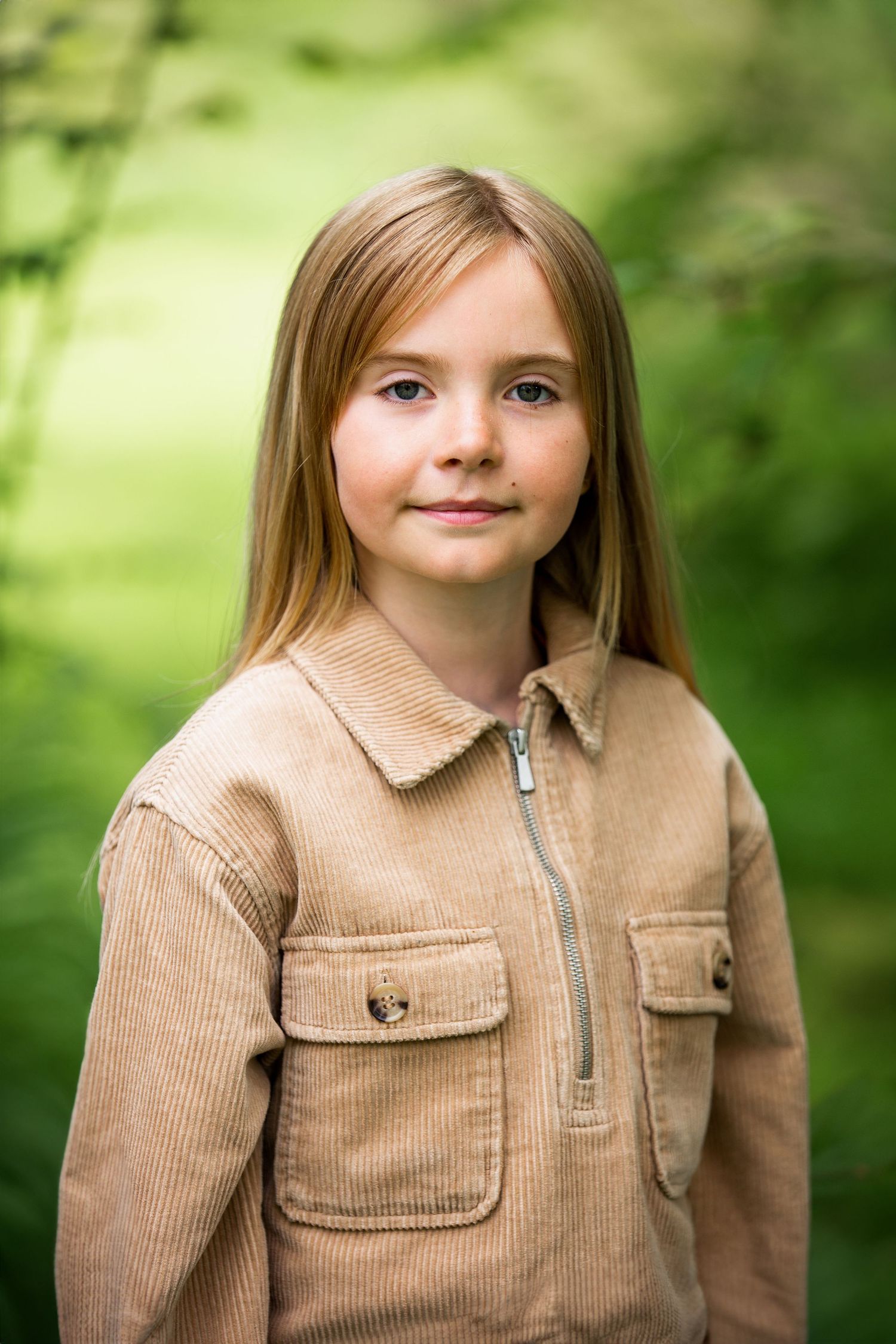 Portrait in corduroy jacket against blurred green nature background.