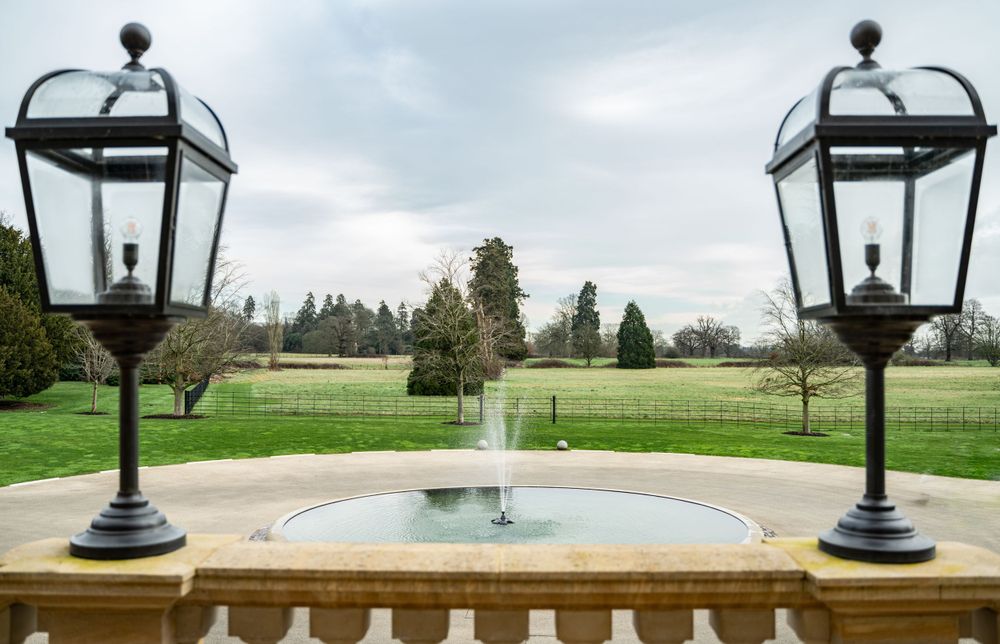 Elegant outdoor lanterns line a path with manicured lawns and gardens in the background.