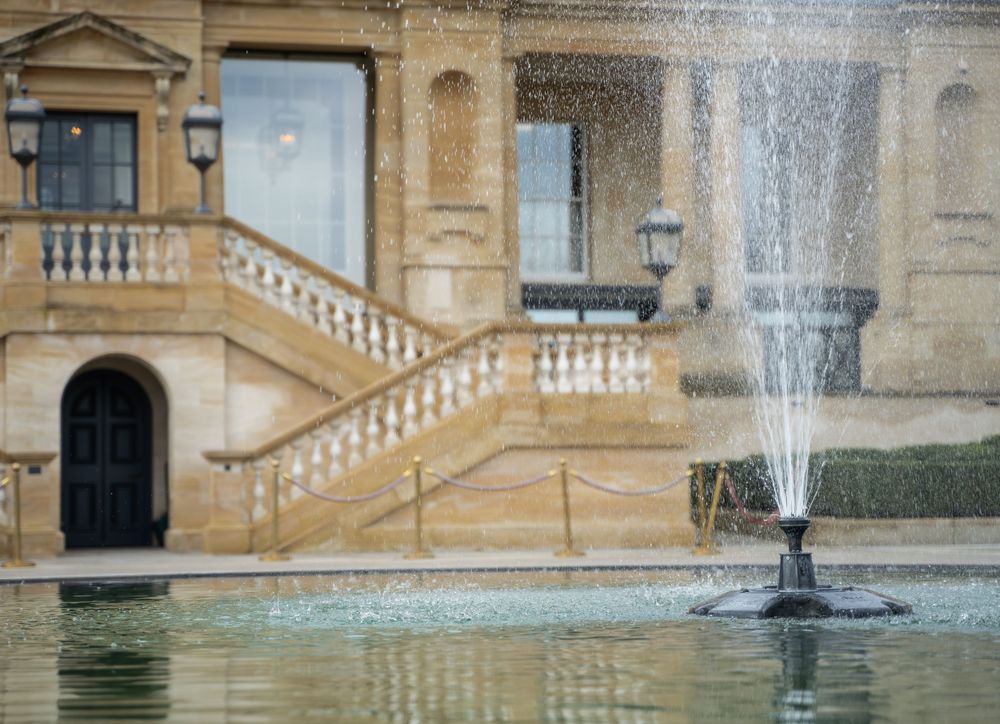 Ornate stone fountain features with cascading water at a historic mansion or estate.