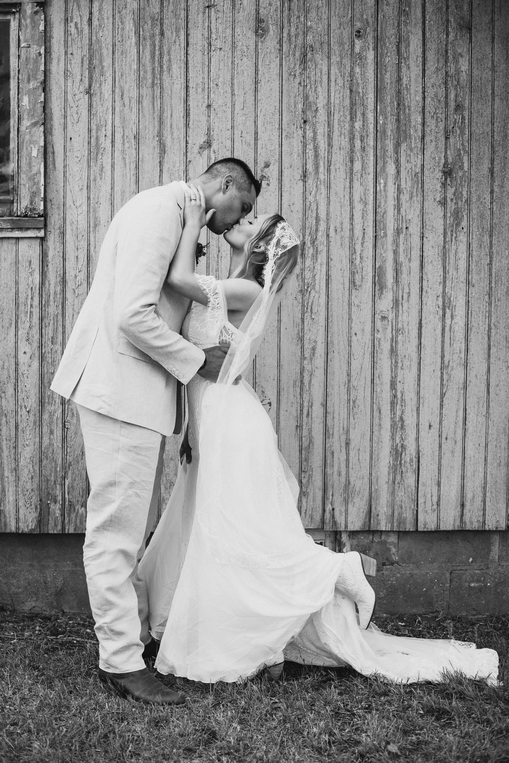 Black and white romantic wedding portrait against rustic barn siding.