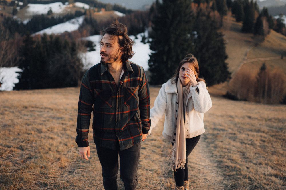 A couple hikes together along a mountain trail during autumn.