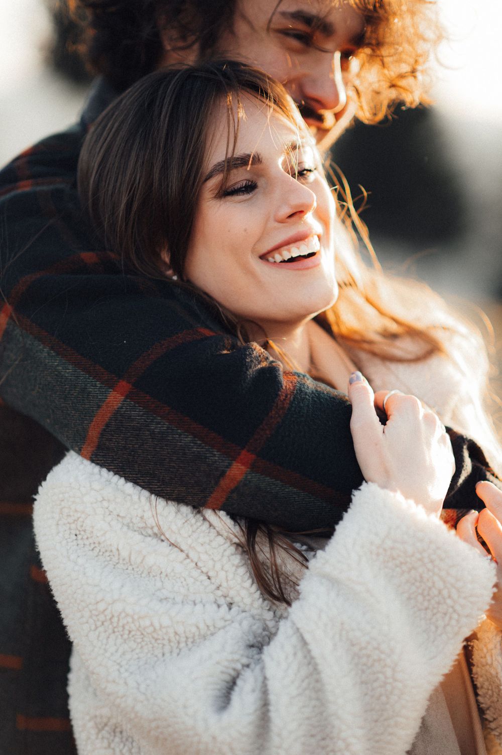 Warm winter moment with soft sunlight and plaid scarf creating cozy atmosphere.