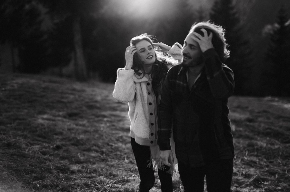 A joyful couple laughing together outdoors during golden hour in black and white photography.